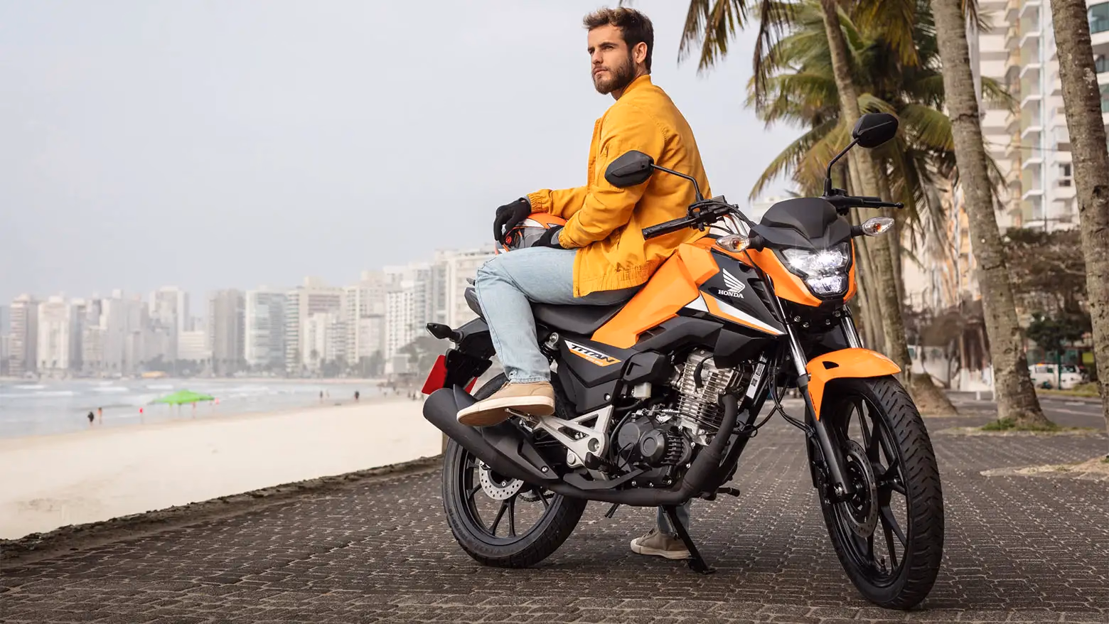Homem observando a paisagem sentado na Honda CG 160 Titan laranja - 5 de 14