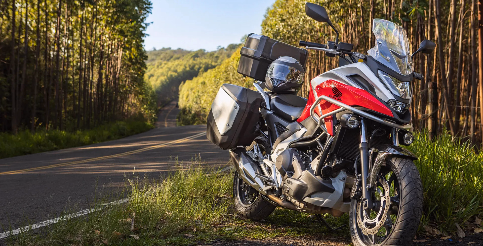 NC 750X vermelha estacionada em gramado ao lado da estrada - 1 de 9
